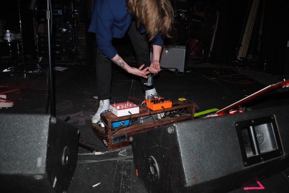 chitarrista di una band shoegaze concentrato sui pedali durante un'esibizione dal vivo